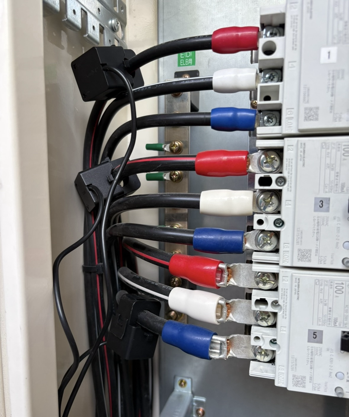 分電盤内の配線にクランプ型CTセンサーを3個挟み込んだ様子